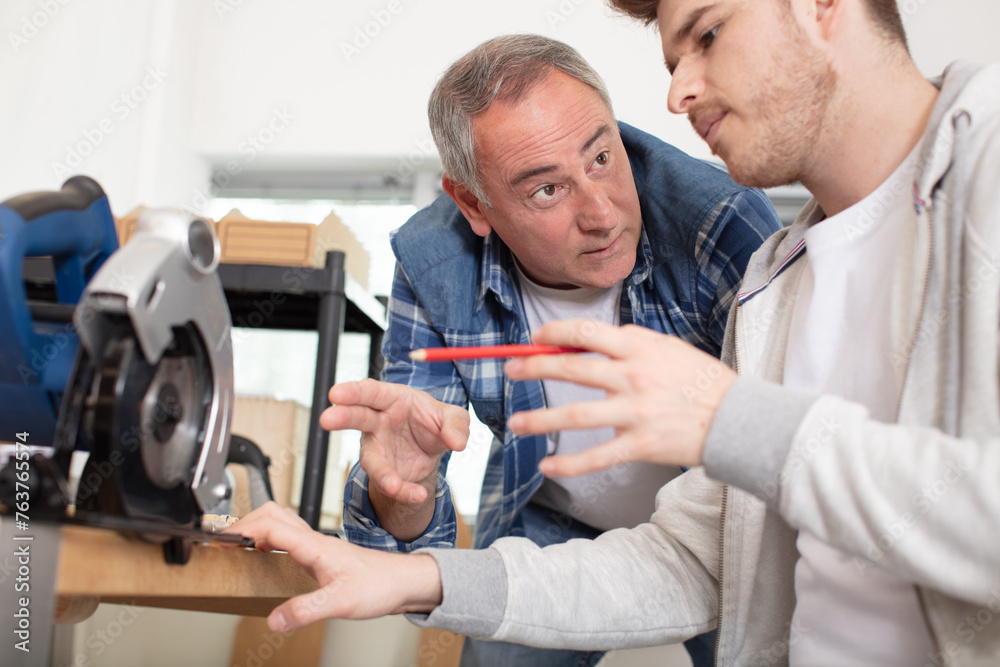 Obraz premium construction workers using slider compound mitre saw