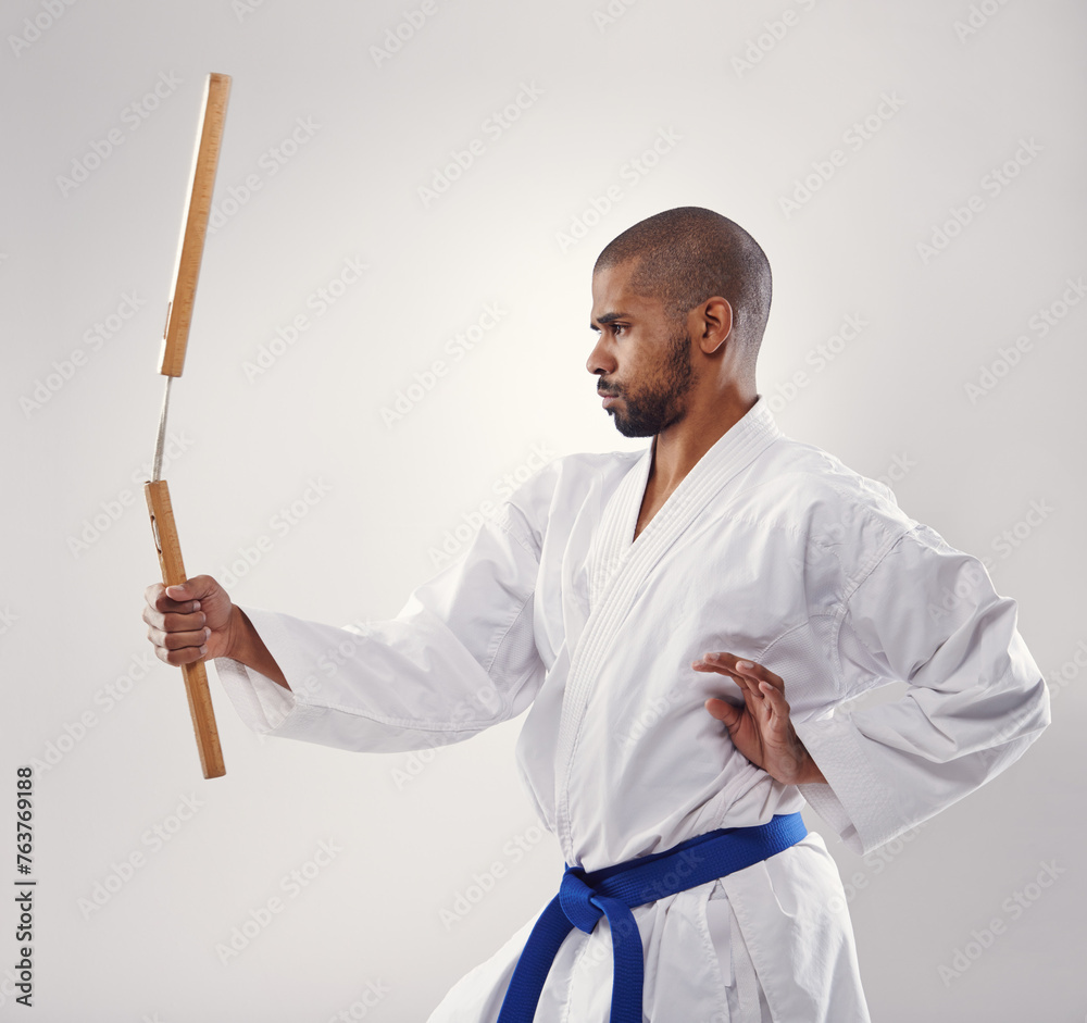 Nunchaku, karate and man in martial arts fight with weapon in training for defence in white background of studio. Nunchucks, exercise and fighting with equipment in sport or gym with creative skill