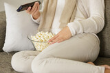 cropped view of woman on sofa with popcorn and remote