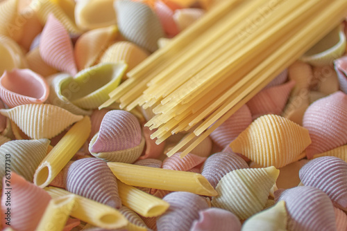 Multicolored italian shell shaped raw pasta and penne, spaghetti composition, decorative background for menu cover design or gastronomic illustration