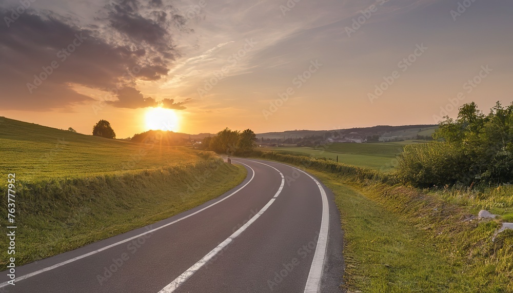 A sunset shines upon a winding asphalt road in Molsheim