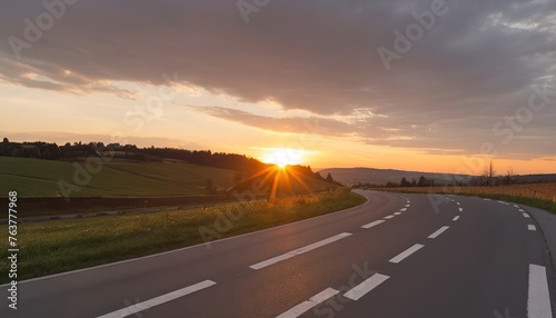 A sunset shines upon a winding asphalt road in Molsheim