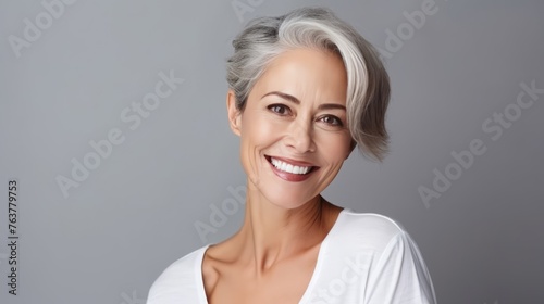 A woman with a short gray hair and a white shirt is smiling