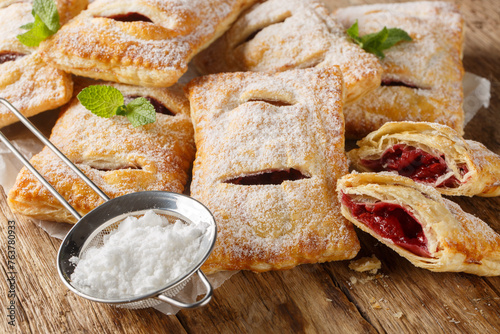 Sweet berry puff pastry with powdered sugar and mint close-up on the table. Horizontal © FomaA