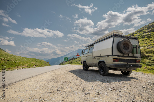 Old vintage expedition camper parked on top of Solkpass in Austria. Beautiful view from the top of mountain pass, asphalt road and gravel parking