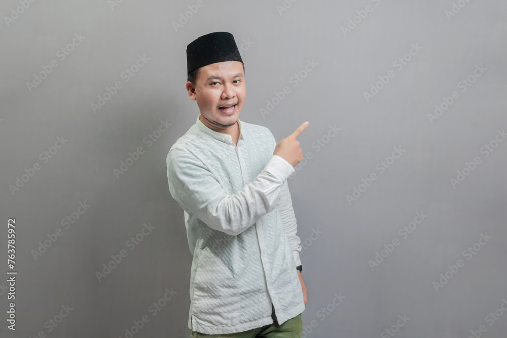 Happy asian muslim man recommend promo as pointing to copy space, indicate down link Happy asian muslim man recommend promo as pointing to copy space, indicate down link