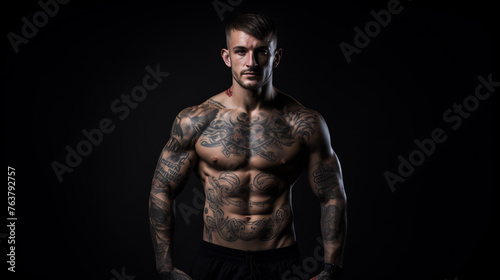 Portrait of a Muscular Tattooed Man with a Focused Expression in Low Key Lighting, Emphasizing the Art of Body Ink and Physical Fitness © AspctStyle