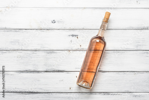 Bottle of rose wine flat lay on a white wooden background. View from above.