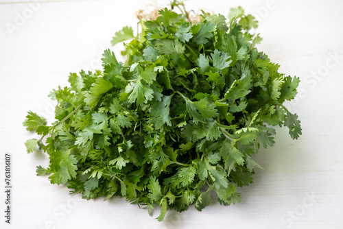 Fresh coriander leaves on a wooden background. Its scientific name is Coriandrum sativum. Locally in Bangladesh, It is called Dhone Pata and also known as cilantro, Chinese parsley, or Mexican parsley photo