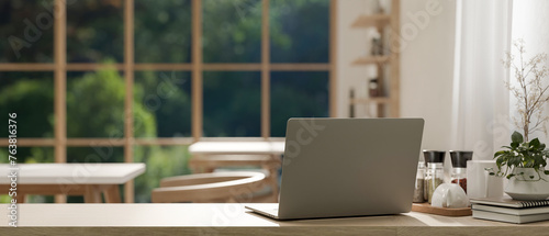 A back view image of a laptop on a wooden table in a cosy Scandinavian coffee shop co-working space