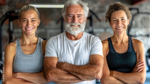 Two women and an older man posing in the gym. photo