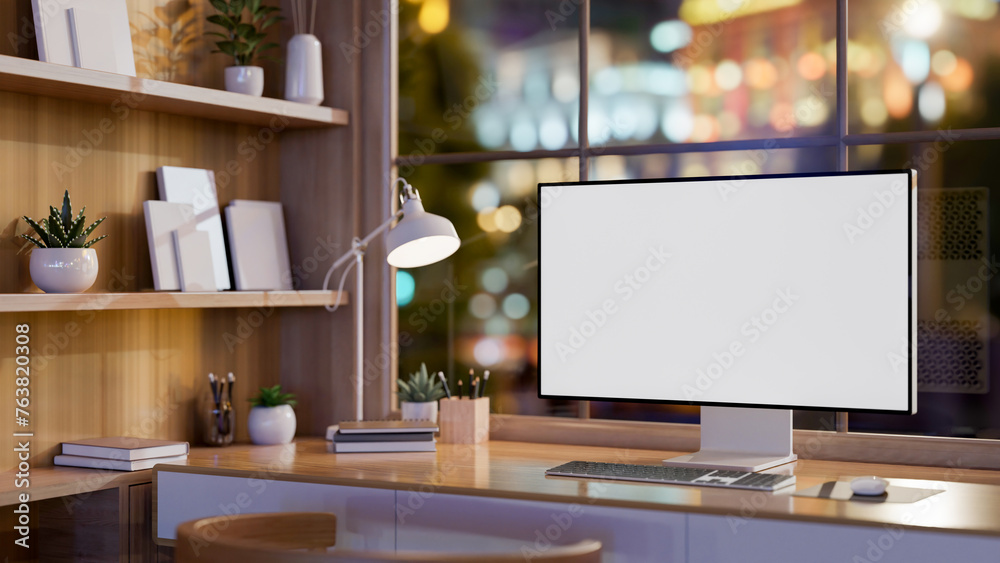 A contemporary office features a computer on a table against the window with a nighttime city view. A contemporary office features a computer on a table against the window with a nighttime city view.