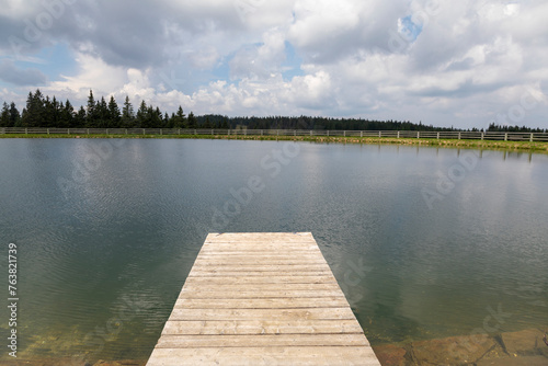 An empty wooden pier by a small lake.
