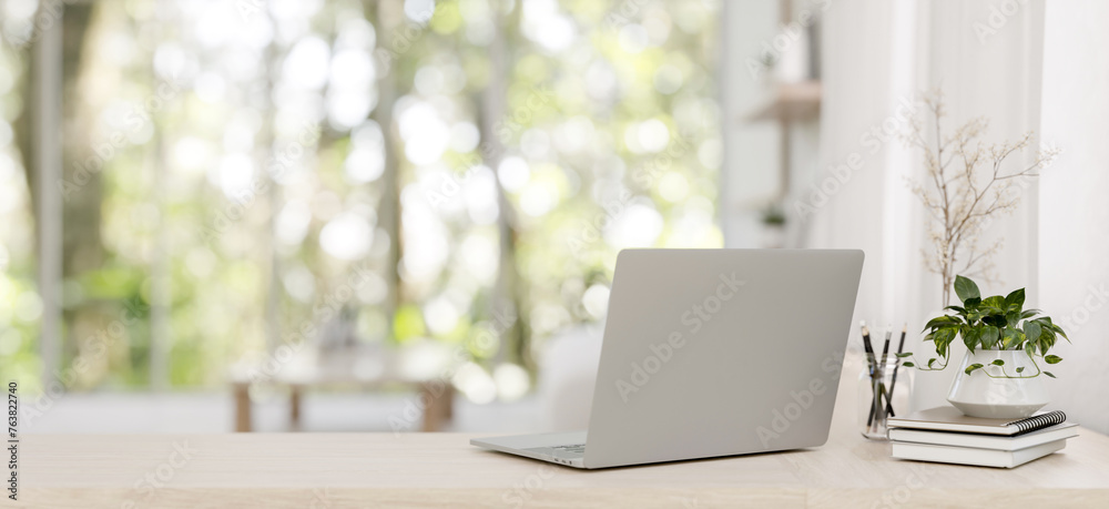 A back view image of a laptop on a wooden desk in a minimalist bright living room. - obrazy, fototapety, plakaty 