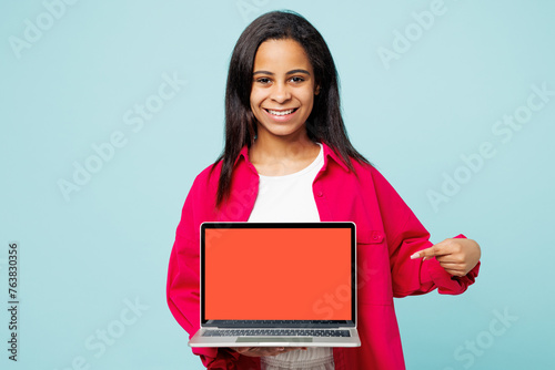 Little kid teen IT girl wear pink shirt white t-shirt hold use work point on blank screen workspace area laptop pc computer isolated on plain pastel blue cyan background. Childhood lifestyle concept.