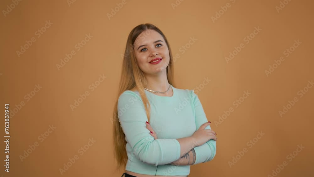 Young woman posing isolated in studio. Smiling cute beautiful adult girl with looking camera crossed her arms at the elbows on background in studio. People emotions lifestyle, young beauty concept. Young woman posing isolated in studio. Smiling cute beautiful adult girl with looking camera crossed her arms at the elbows on background in studio. People emotions lifestyle, young beauty concept.
