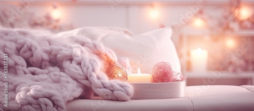 A pink fur blanket drapes over a magenta couch with a peach scented candle resting on a stylish wood side table. The cozy ambiance is enhanced by the warm lighting and art on the walls