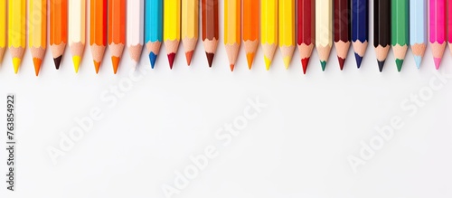 Many colorful crayons lined up on a white surface