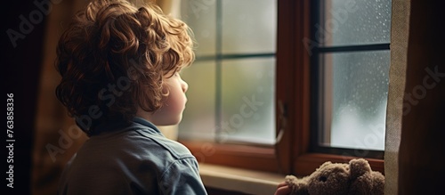 Boy observing rain from a window