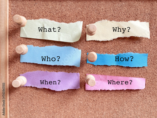 What why who how when where questions on torn papers background. Stock photo.