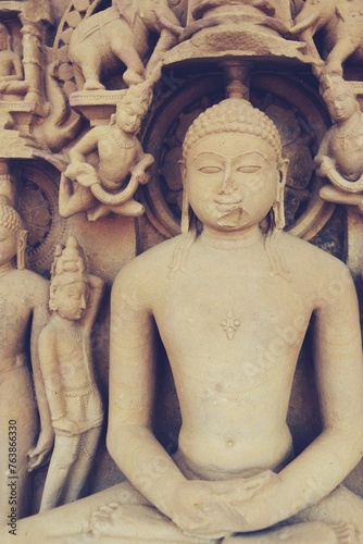 A finely detailed stone sculpture of a Jain Tirthankara ADINATH, with a serene expression, surrounded by ornate carvings photo