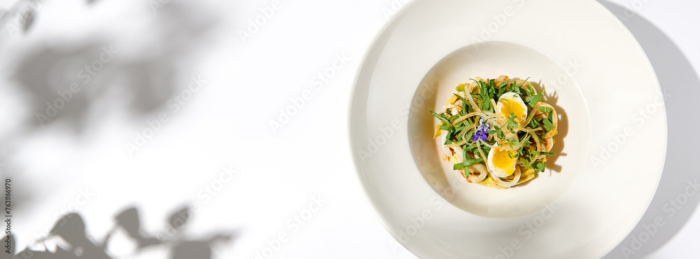 Healthy salad with squid and avocado on white plate with harsh shadows. Calamari salad with vegetables and eggs on white background with shadows of leaves. Summer food menu. Healthy salad with squid and avocado on white plate with harsh shadows. Calamari salad with vegetables and eggs on white background with shadows of leaves. Summer food menu.