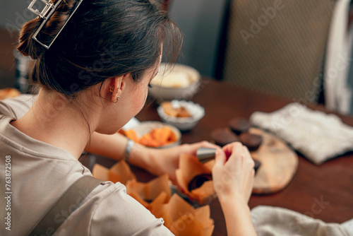 A young woman makes indentations in cupcakes for filling. the concept of baking at home in the kitchen for a birthday. copy space