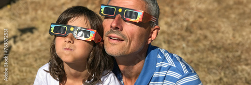 Father and daughter looking at the sun during a solar eclipse on a country park, family outdoor activity © jovannig