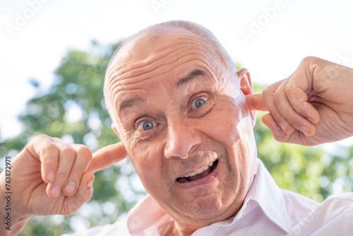 senior, funny man 65 years old holds to ear, male face, facial expression, auditory hallucinations, earache, hearing loss, deafness, Acute otitis media, acoustic trauma, auditory processing disorder photo