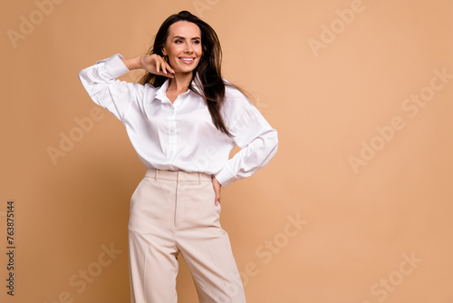 Photo of gorgeous peaceful cheerful girl hand touch face look empty space isolated on beige color background