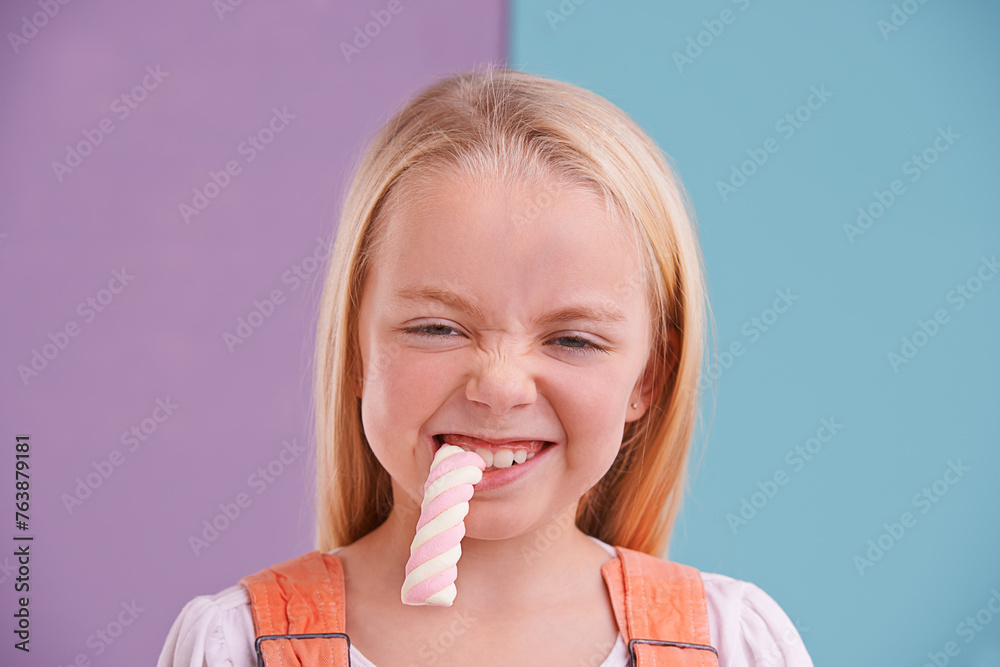 Studio, girl and candy with marshmallow, dessert and hungry for snack and childhood. Child, sweets and yummy food for tasty, eating and happiness on vibrant split pastel pink and blue background