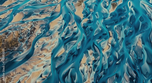 Aerial view of the surreal blue and beige patterns on rivers in Iceland, creating an abstract aerial landscape