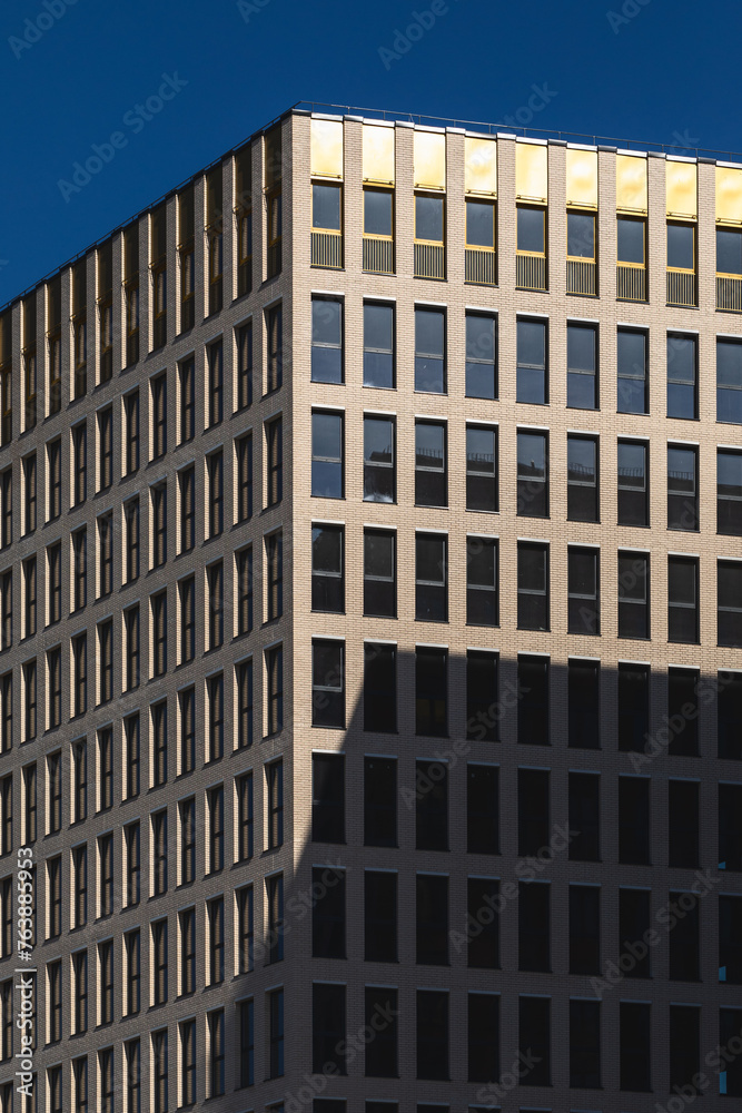 Fototapeta premium Facade of modern building. Bright sunlight and blue sky background.
