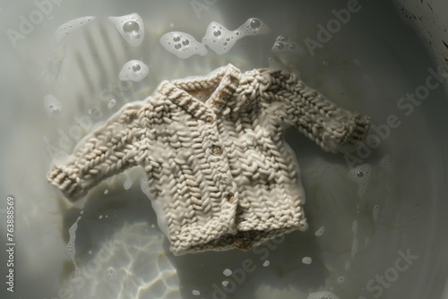 a babys knitted cardigan floating in warm, sudsy water