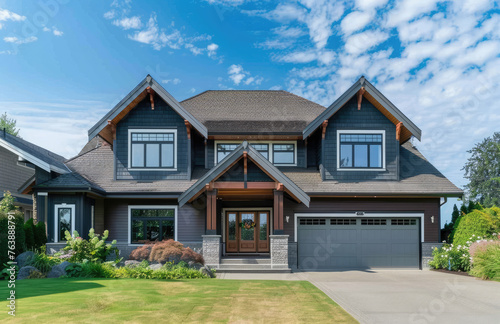 Beautiful two story luxury home in the British Columbia region of Canada, with blue sky and green grass. The house has shingle roof tiles, white windows, gray walls