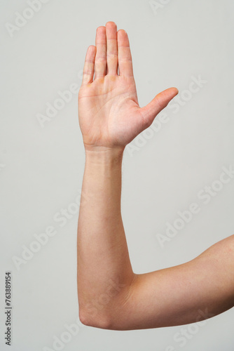 Male hand showing five fingers against gray background