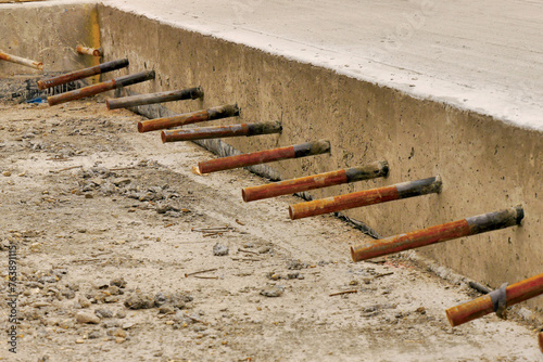 concrete slab edge showing steel dowel bars in a row.