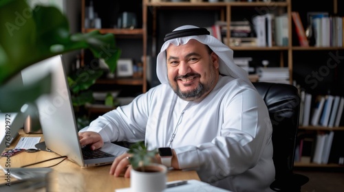 Smiling Emirati Businessman Working on Laptop