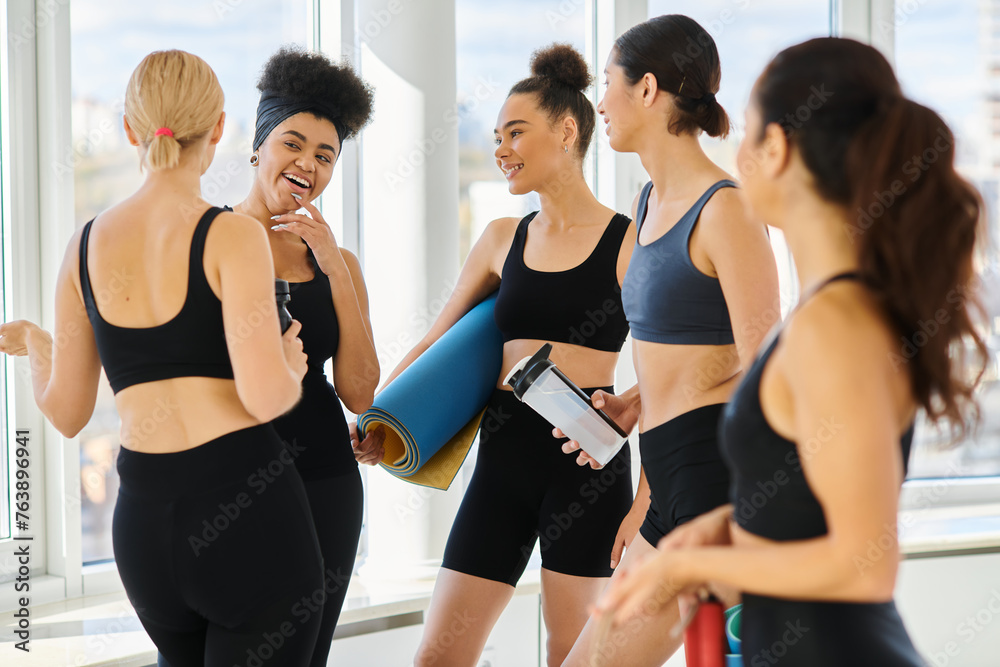 five joyful and young multicultural women in active wear chatting after workout in pilates studio five joyful and young multicultural women in active wear chatting after workout in pilates studio