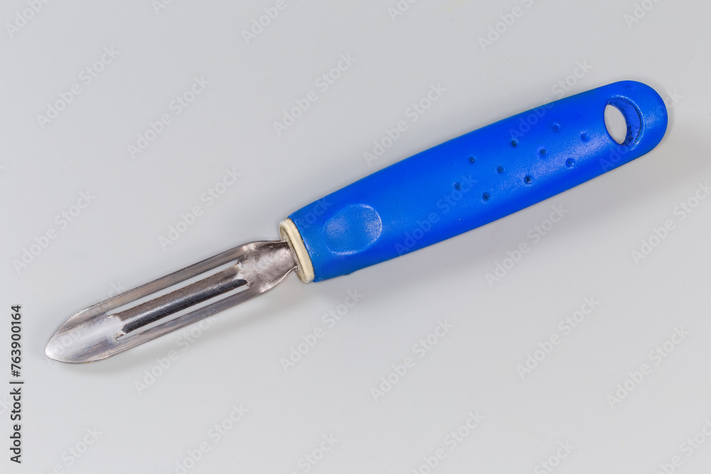 Vegetable peeler with straight fixed blade on a gray background Vegetable peeler with straight fixed blade on a gray background