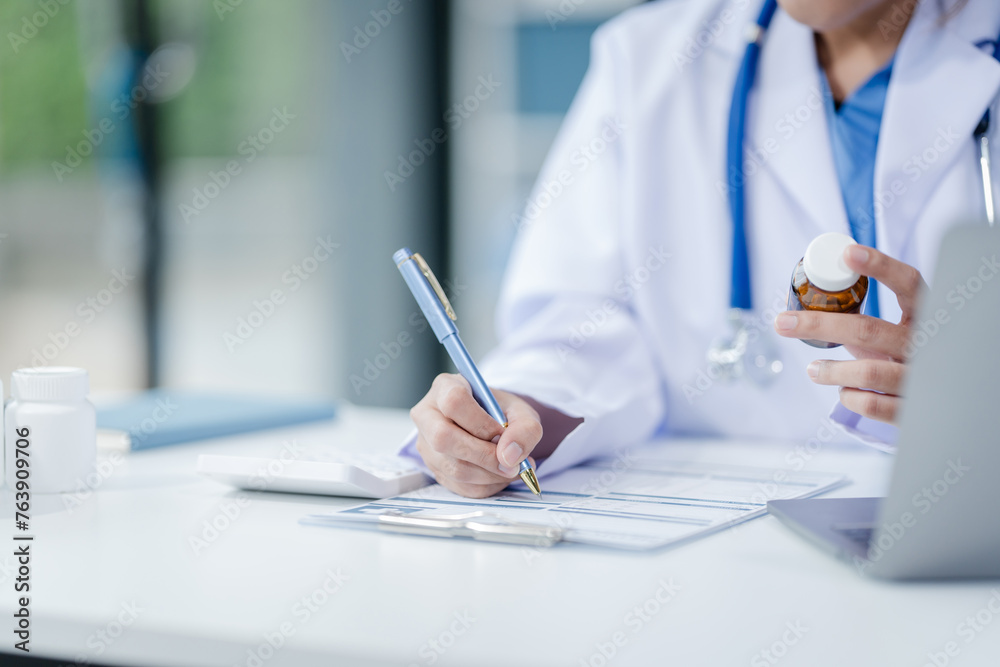 Portrait of mix race asian middle age female doctor in white lab coat and stethoscope while consult online in laptop. advice on good mental health management and medical treatment costs. Portrait of mix race asian middle age female doctor in white lab coat and stethoscope while consult online in laptop. advice on good mental health management and medical treatment costs.
