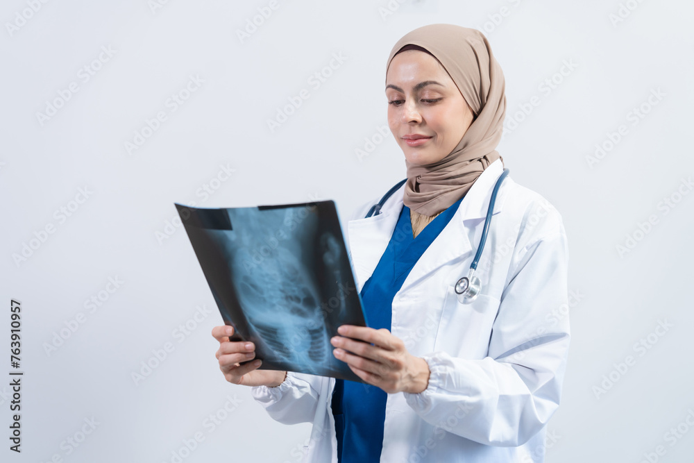 Asian Muslim doctor in hijab and scrubs headphones around her neck Stand confidently in the medical office, isolated on white background, holding x-ray film. Asian Muslim doctor in hijab and scrubs headphones around her neck Stand confidently in the medical office, isolated on white background, holding x-ray film.