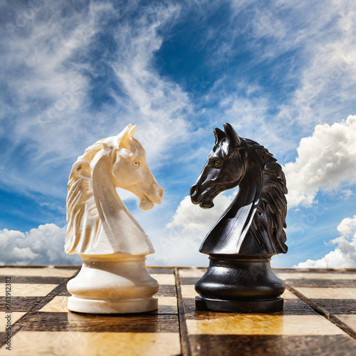 two chess knights, black and white, facing each other on the chessboard