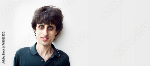 Horizontal banner representing a person with rare disease, friendly disabled man in casual outfit smiling isolated on white background, studio photograph of a guy with handicap and blank space photo