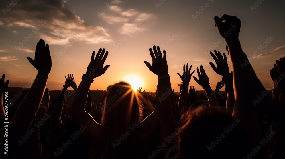 A group of people captured in silhouette, raising their hands in celebration against the warm glow of a setting sun, conveying a sense of freedom and joy