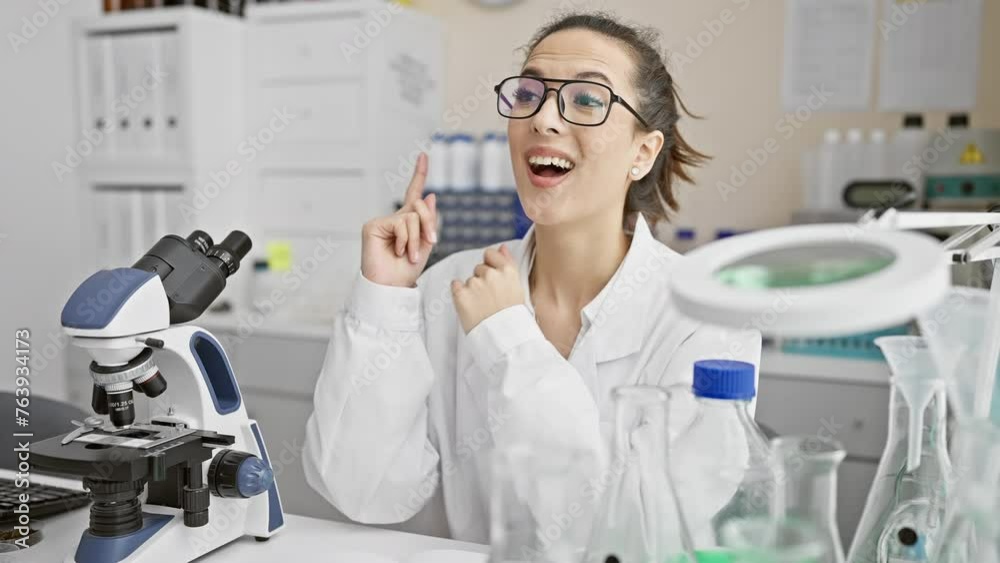 Cheery, stunning young hispanic woman wearing scientist uniform gives thumbs up, points to question with happy face in lab, innovator no.1! Cheery, stunning young hispanic woman wearing scientist uniform gives thumbs up, points to question with happy face in lab, innovator no.1!