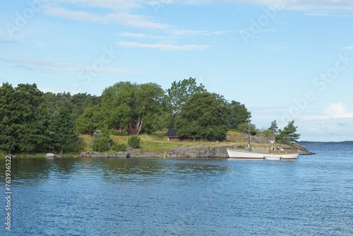 Old sailing boat moored to a pier on the island of Jussarö in summer with clouds in the sky, Raasepori, Finland.