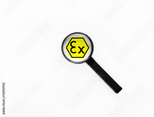 Magnifying glass zooming on a ATEX sign to focus on protecting manufacturer employees and users on the workplace