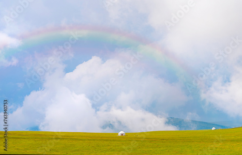 Beautiful nature of Kazakhstan on the Assy plateau. White yurt under the rain clouds and rainbow.