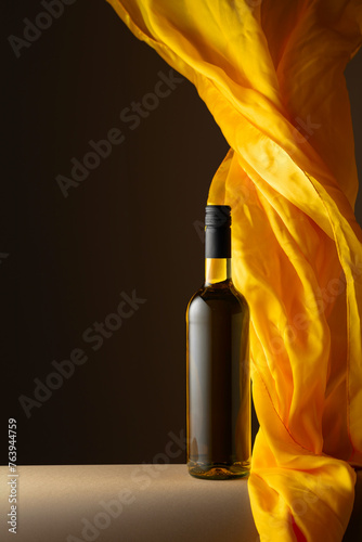 Bottle of white wine and flutters of yellow cloth.